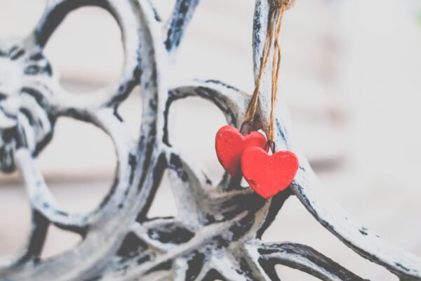 Two small red hearts on a string hanging on an ornamental bench